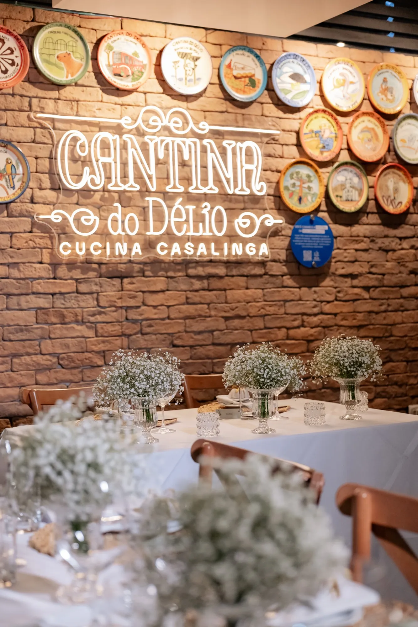 Salão da Cantina preparado para um casamento, com flores nas mesas e a parede de pratos ao fundo